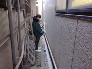 壁沿いで漏水調査する女性調査員